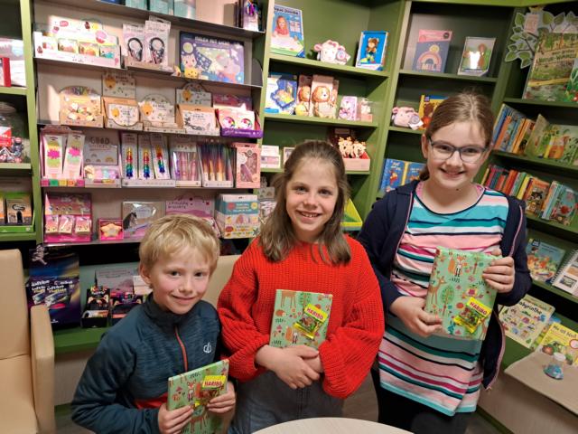 Johannes (6), Elisa Marie (10) und Hanna (9) nehmen in der Buchhandlung Lesezeichen ihre Gewinne entgegen