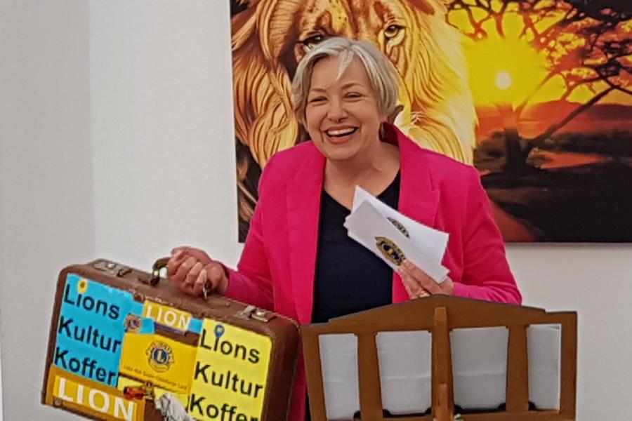 Antrud Schröder mit dem Lions Kulturkoffer … vor einem Löwenposter des Seniorensitzes